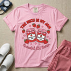 A t-shirt featuring two jars of strawberry jam surrounded by small hearts and strawberries with the text THE NICU IS MY JAM arched above and Neonatal ICU Nurse written in a retro script below.
