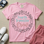 A postpartum nursing t-shirt featuring the stacked text "Fourth Trimester Crew" in blue and pink retro fonts, surrounded by a circular border of white minimalist line drawings depicting newborn and postpartum care items including a breast pump, swaddled baby, maternity bra, maxi pad, stethoscope, wipes, and a nursing pillow.