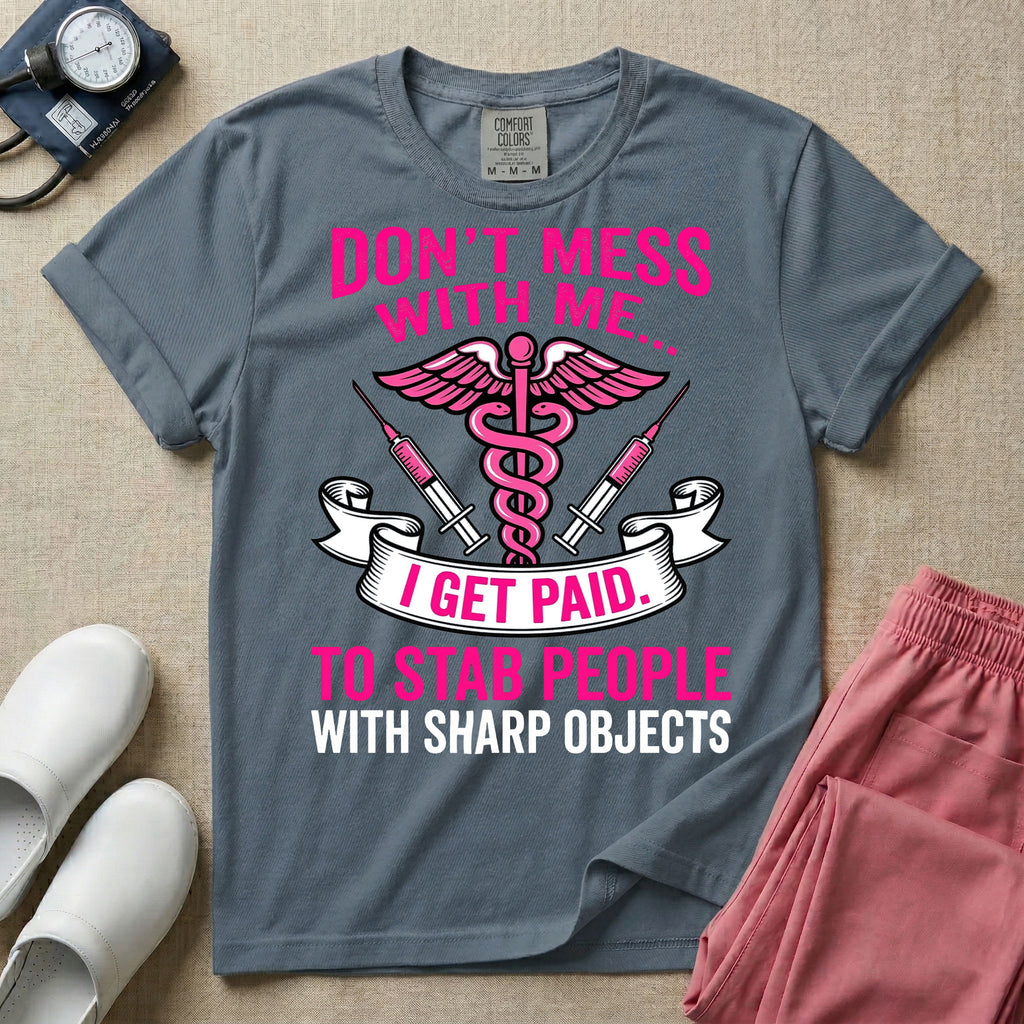 General nursing and ER t-shirt featuring a pink and black caduceus medical symbol flanked by two syringes alongside the humorous text "DON'T MESS WITH ME... I GET PAID TO STAB PEOPLE WITH SHARP OBJECTS".