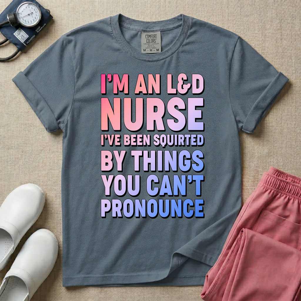 A humorous graphic tee for labor and delivery nurses featuring bold, gradient block lettering that reads "I'M AN L&D NURSE I'VE BEEN SQUIRTED BY THINGS YOU CAN'T PRONOUNCE".
