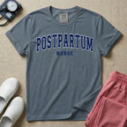 A t-shirt featuring the word POSTPARTUM arched in large collegiate block letters above the word NURSE in a smaller, matching font.