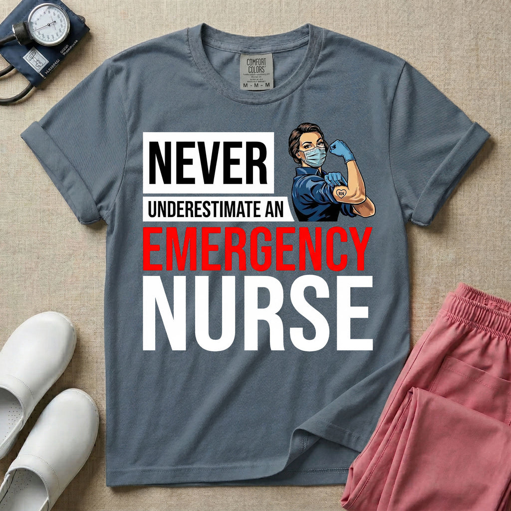 A retro ER nursing t-shirt featuring the bold text "NEVER UNDERESTIMATE AN EMERGENCY NURSE" alongside a vintage graphic of a masked nurse flexing her arm in a classic Rosie the Riveter pose