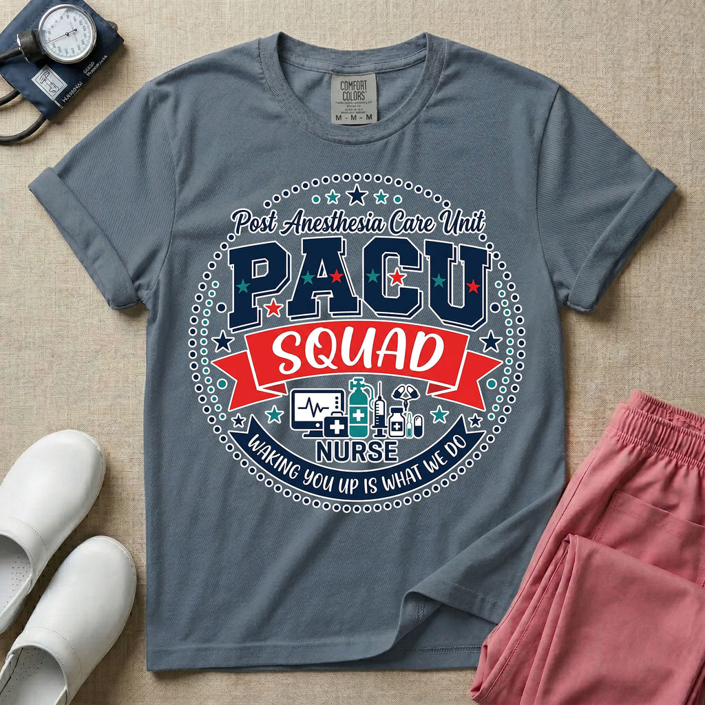 A t-shirt featuring a circular badge design with the text PACU SQUAD in block letters, medical icons like a heart monitor and stethoscope, and the phrase Waking You Up Is What We Do.