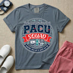 A t-shirt featuring a circular badge design with the text PACU SQUAD in block letters, medical icons like a heart monitor and stethoscope, and the phrase Waking You Up Is What We Do.