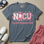 Retro coquette style t-shirt graphic featuring decorative pink 'NICU' text with checkerboard and heart patterns, incorporating a baby bottle with a bow and hearts, and the cursive text 'Neonatal Intensive Care Unit' below.