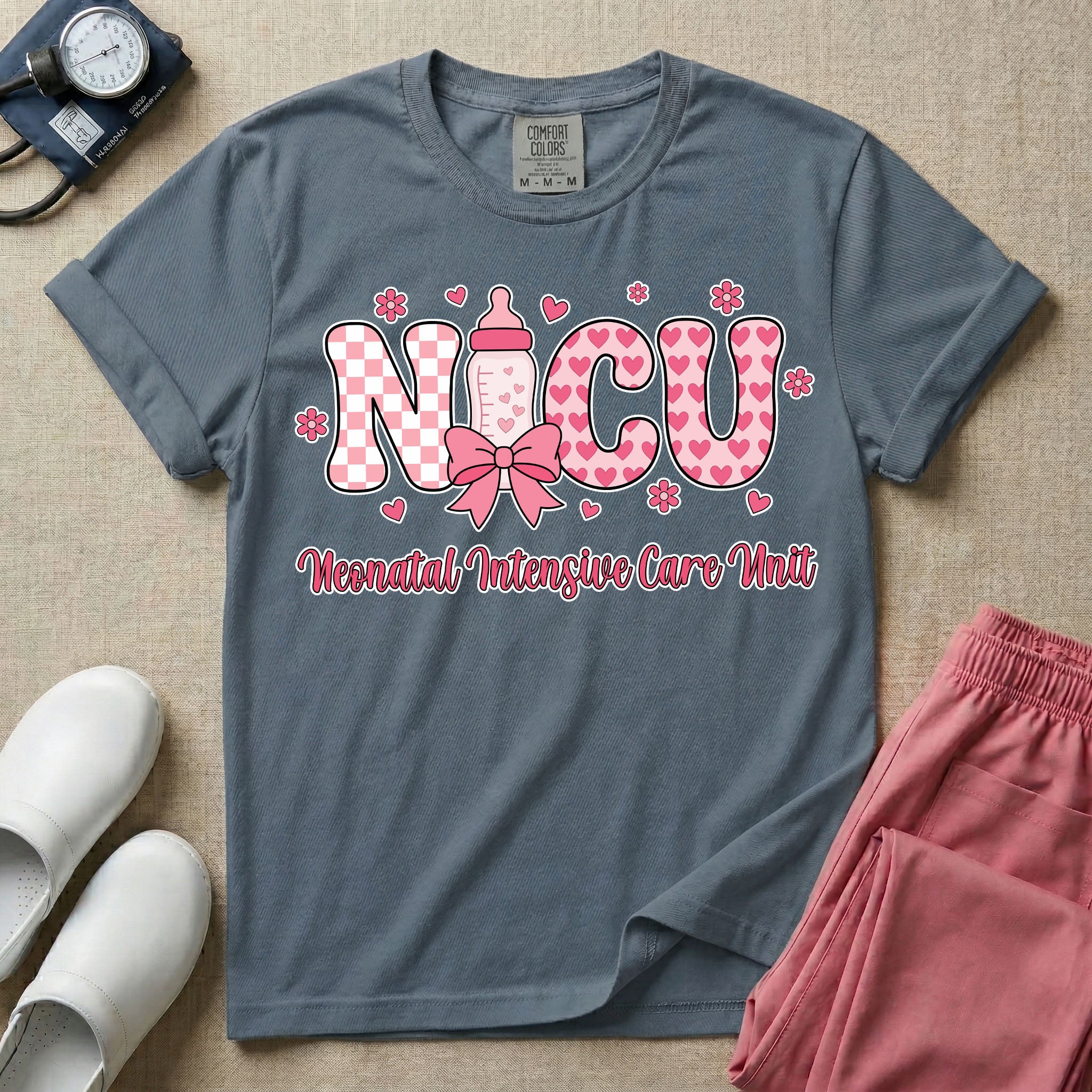 Retro coquette style t-shirt graphic featuring decorative pink 'NICU' text with checkerboard and heart patterns, incorporating a baby bottle with a bow and hearts, and the cursive text 'Neonatal Intensive Care Unit' below.