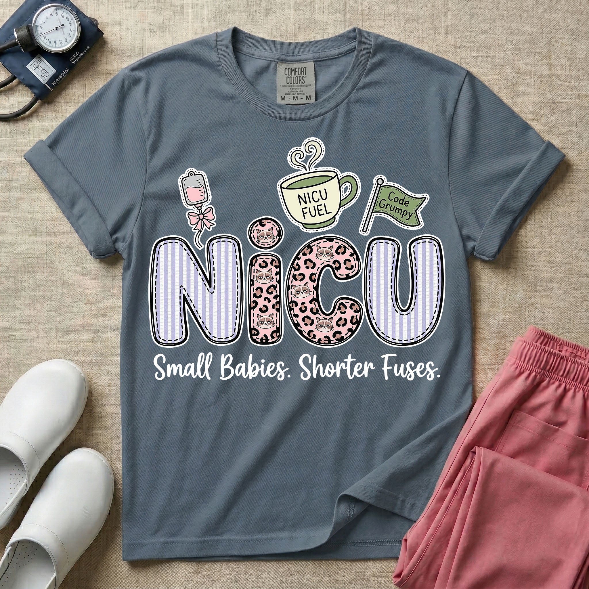 A funny t-shirt for NICU nurses featuring the large text "NICU" patterned with purple stripes and pink leopard print containing grumpy cat faces, accompanied by graphics of an IV bag with a pink bow, a steaming coffee cup reading "NICU FUEL", a green flag saying "Code Grumpy", and the bottom text "Small Babies. Shorter Fuses."