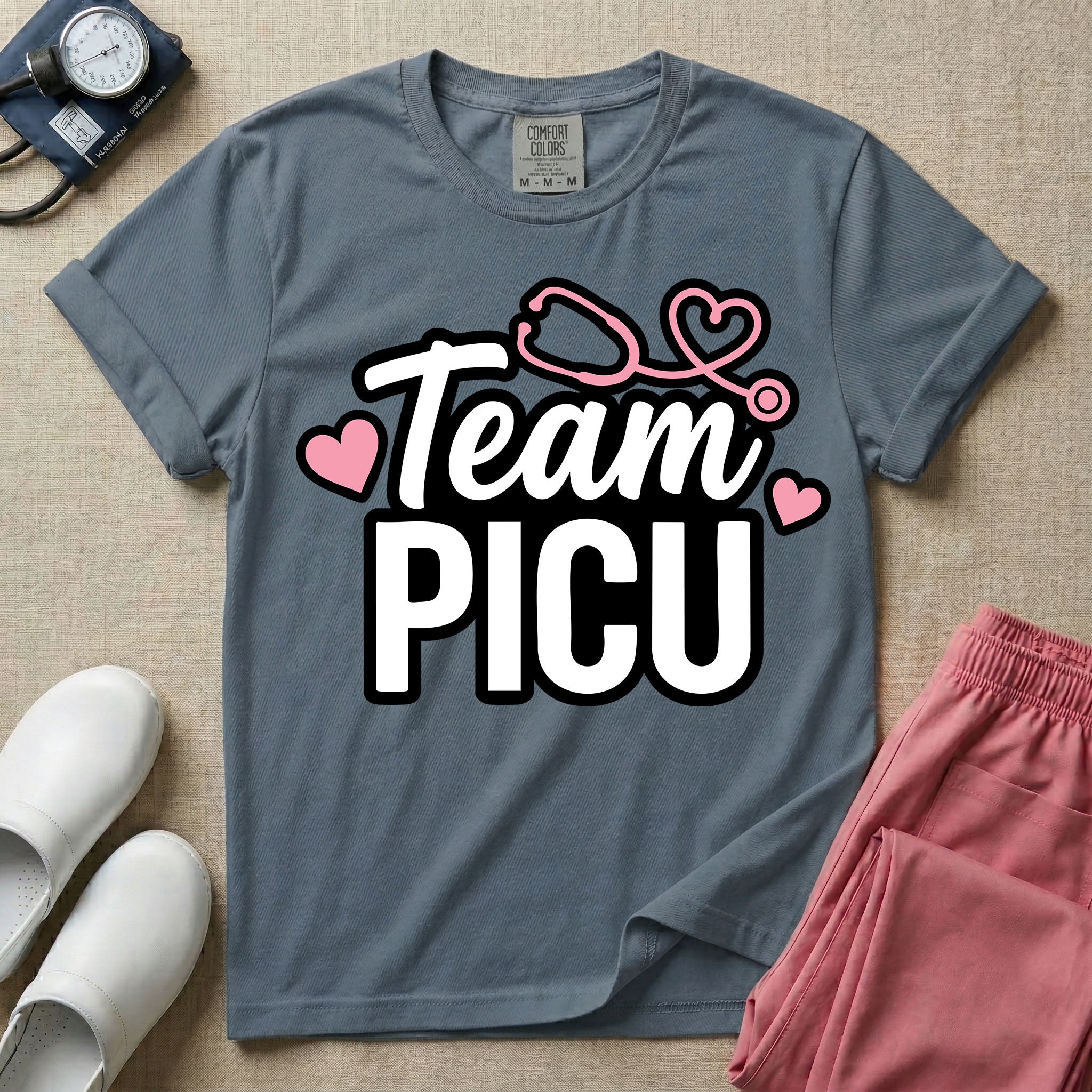 A descriptive graphic tee for pediatric intensive care nurses featuring the text "Team PICU" in bold white lettering, accented with pink hearts and a pink stethoscope design.