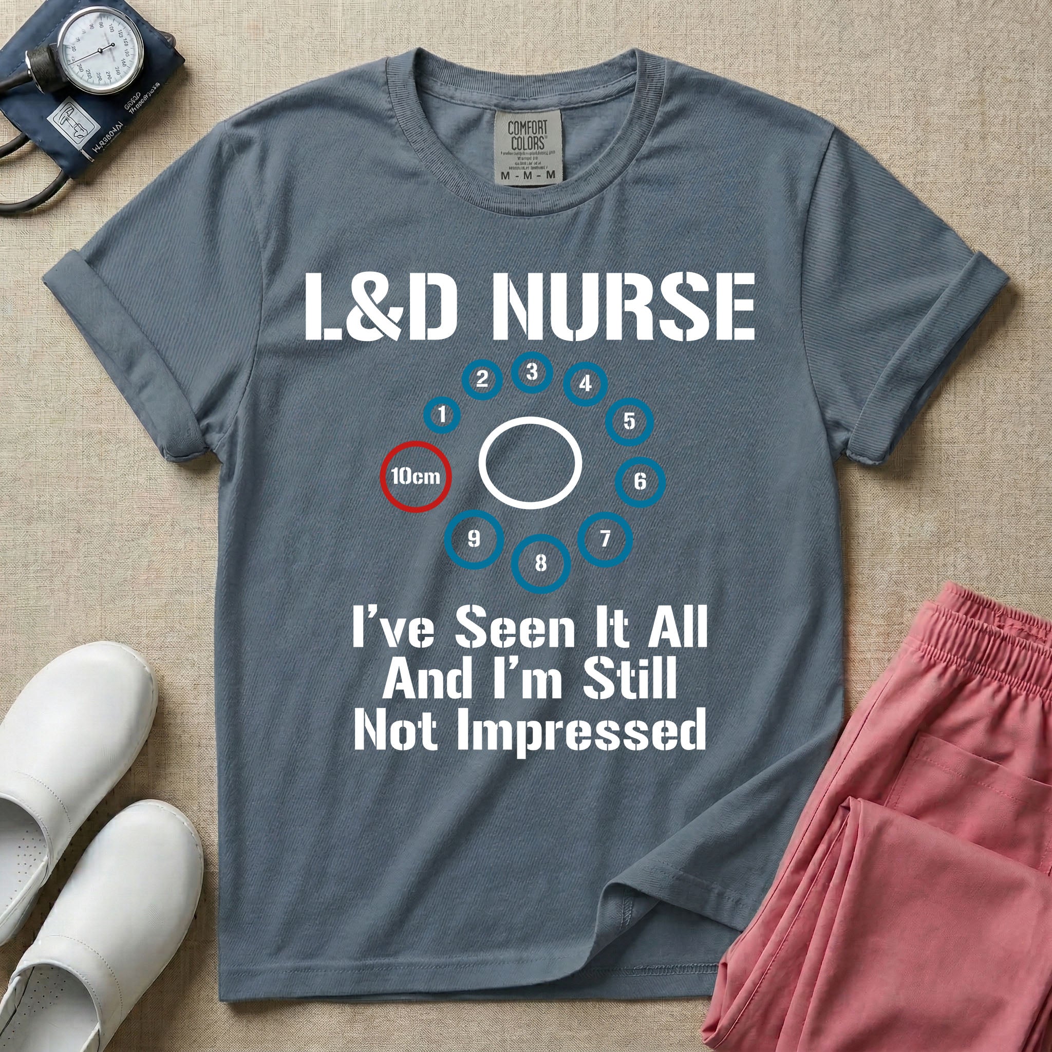 A humorous Labor and Delivery nurse t-shirt featuring a cervical dilation chart graphic highlighting 10cm, with the text "L&D NURSE" at the top and "I've Seen It All And I'm Still Not Impressed" at the bottom.