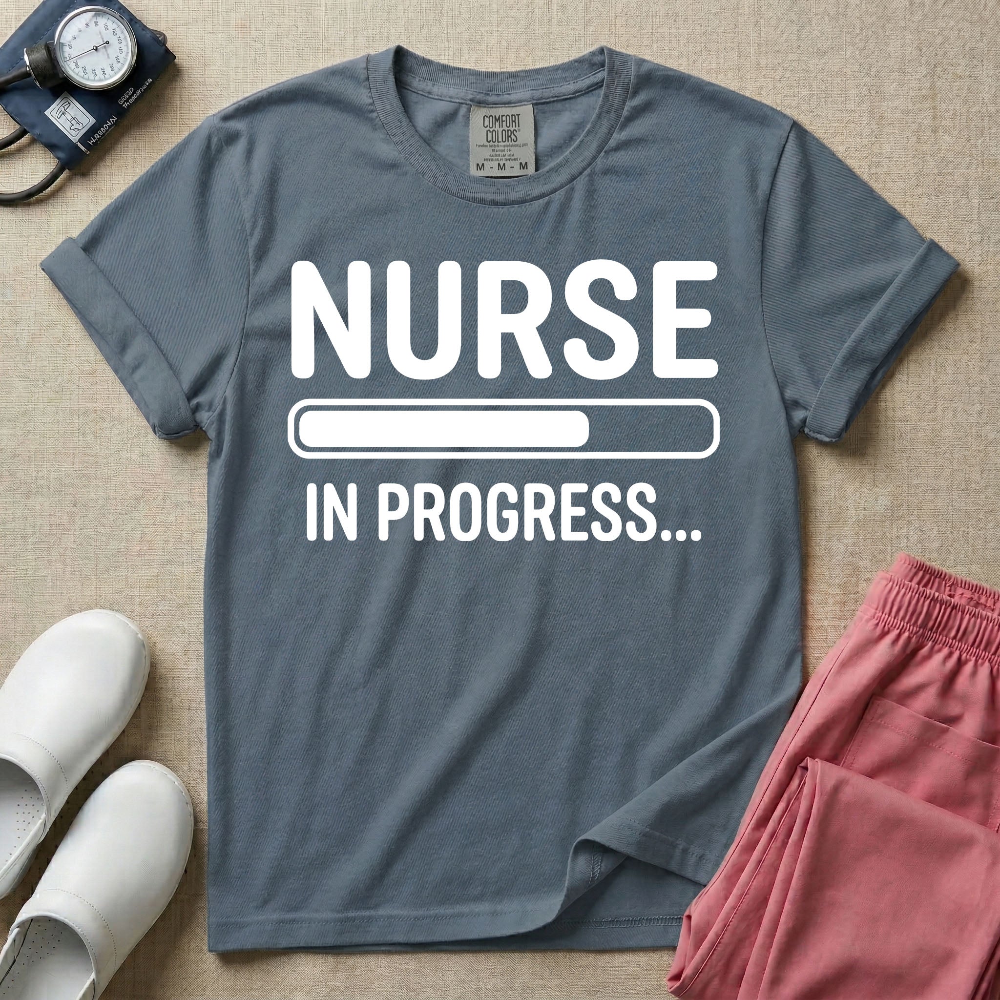 General nursing student t-shirt featuring a white loading bar graphic and the text "NURSE IN PROGRESS..." on a dark gray garment, in blue jean color.