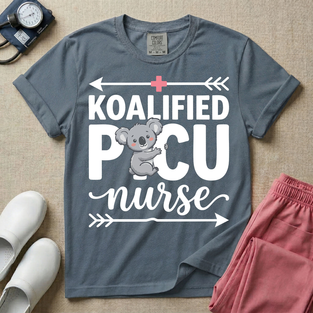 A funny pediatric intensive care nursing t-shirt featuring the pun text "KOALIFIED PICU nurse" with a cute koala graphic replacing the letter I in PICU, framed by decorative arrows and a pink medical cross.