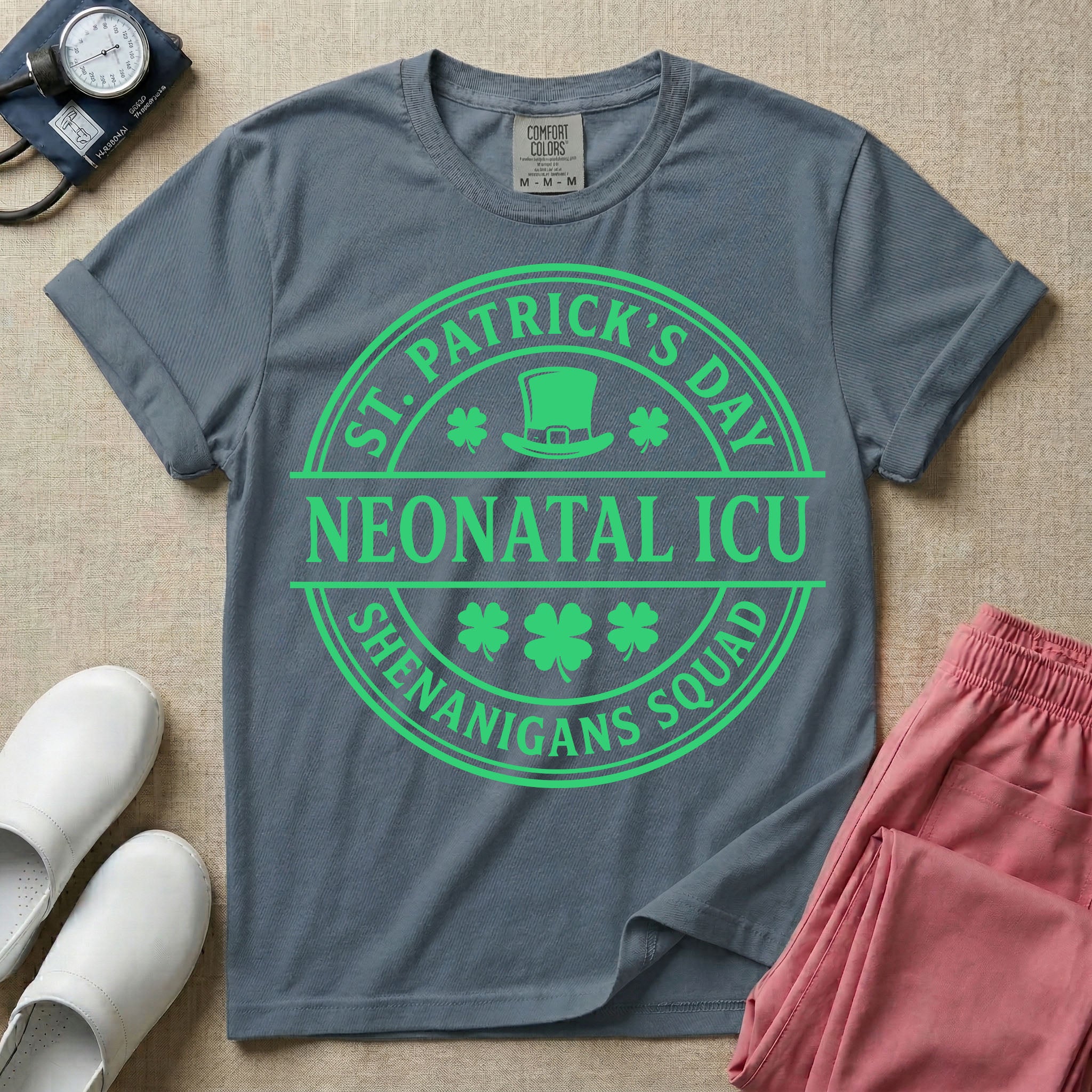 A circular green graphic featuring a leprechaun hat, shamrocks, and the text ST. PATRICK'S DAY SHENANIGANS SQUAD surrounding a center banner that reads NEONATAL ICU.
