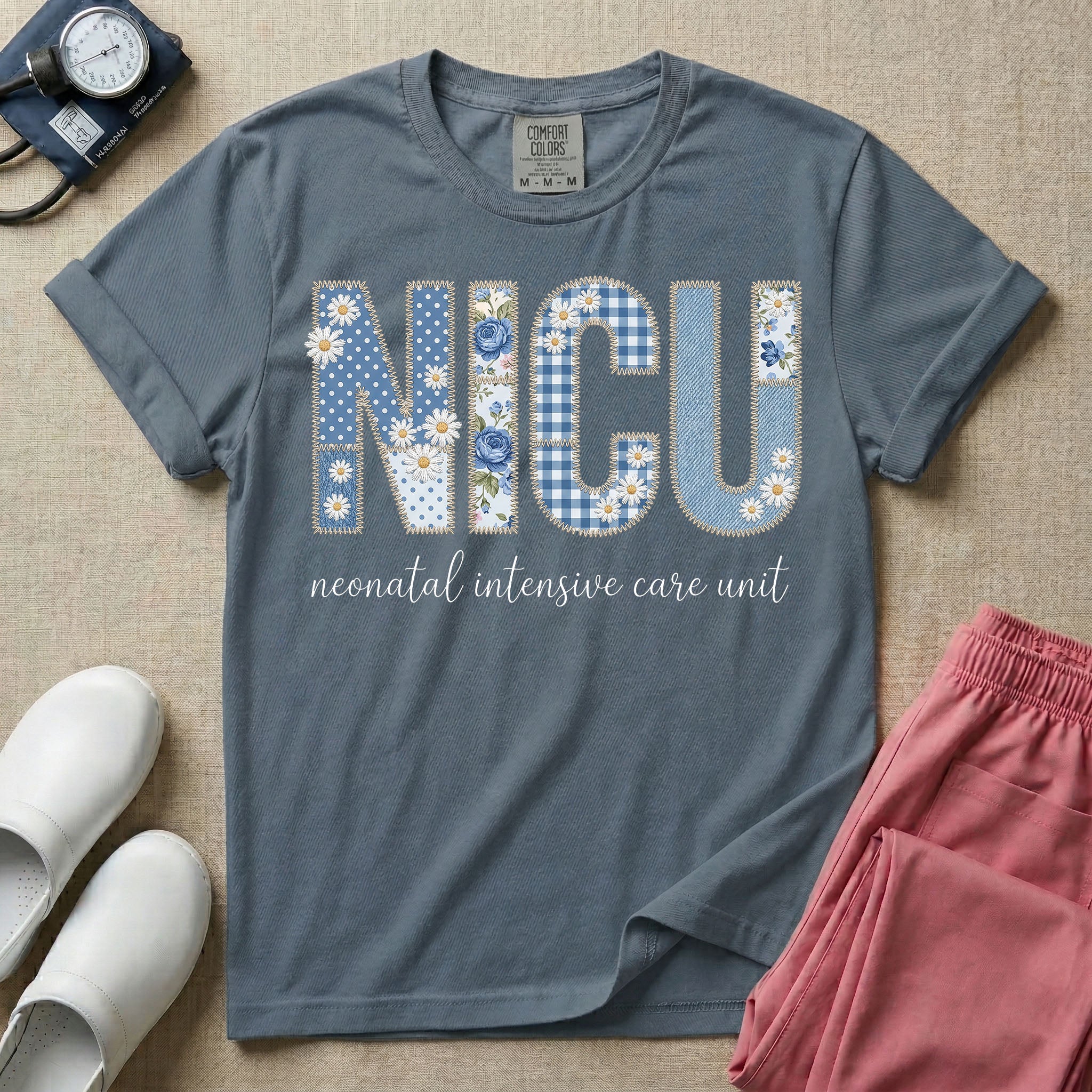 Neonatal Intensive Care Unit NICU nursing t-shirt featuring a faux-embroidery graphic of the letters NICU filled with blue floral and checkered patterns, positioned above the cursive text "neonatal intensive care unit".