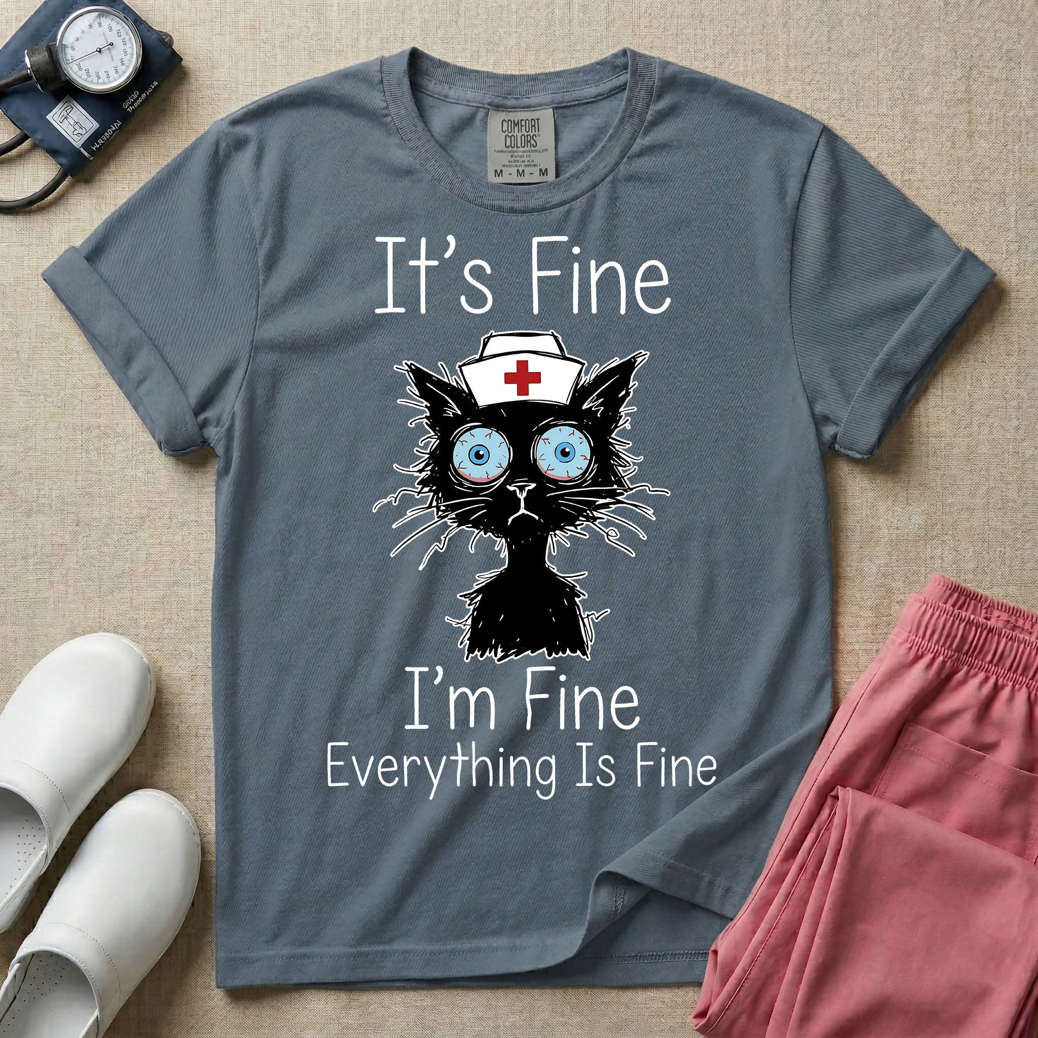General nursing t-shirt featuring a humorous graphic of a frazzled black cat wearing a medical cross nurse cap alongside the text "It's Fine I'm Fine Everything Is Fine".