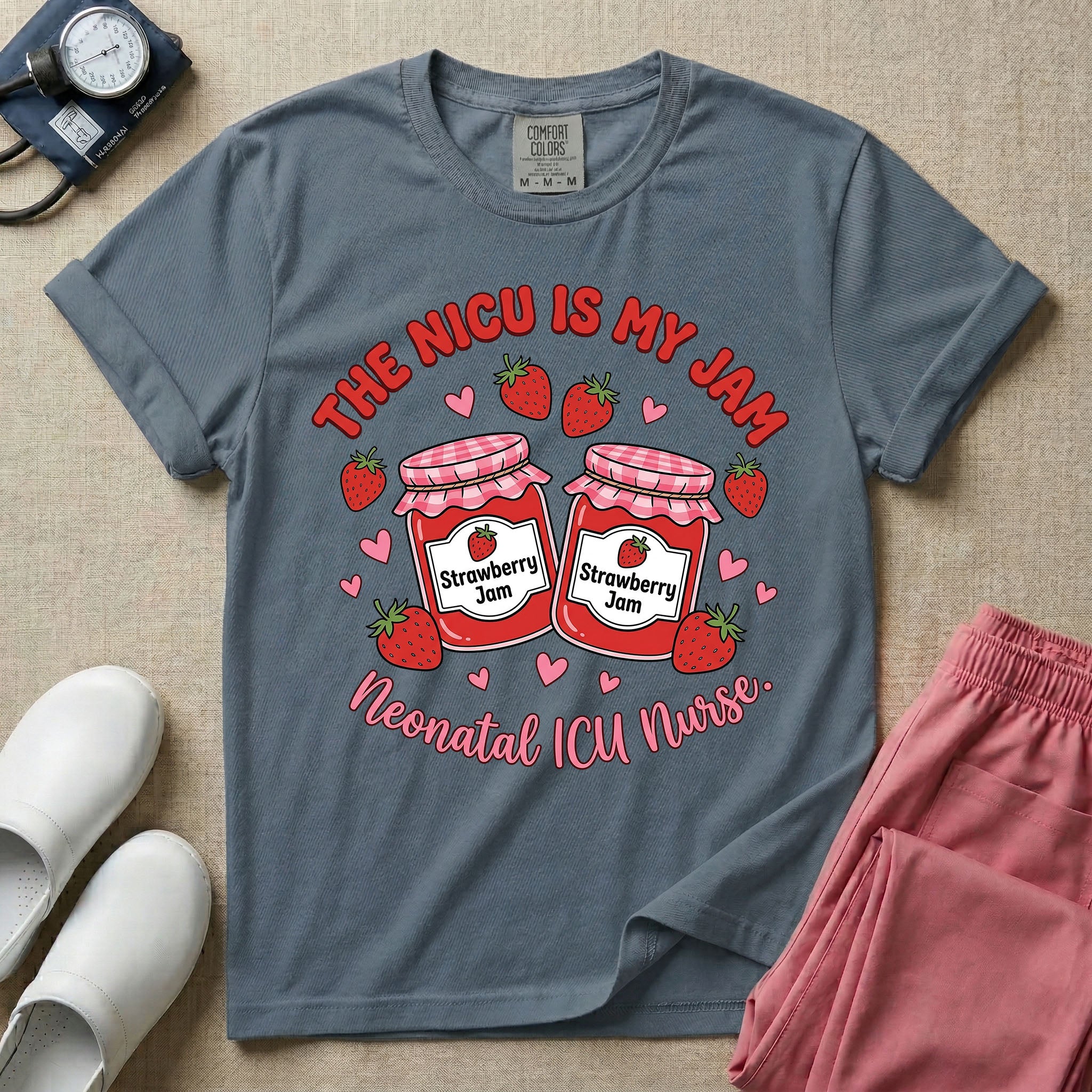 A t-shirt featuring two jars of strawberry jam surrounded by small hearts and strawberries with the text THE NICU IS MY JAM arched above and Neonatal ICU Nurse written in a retro script below.