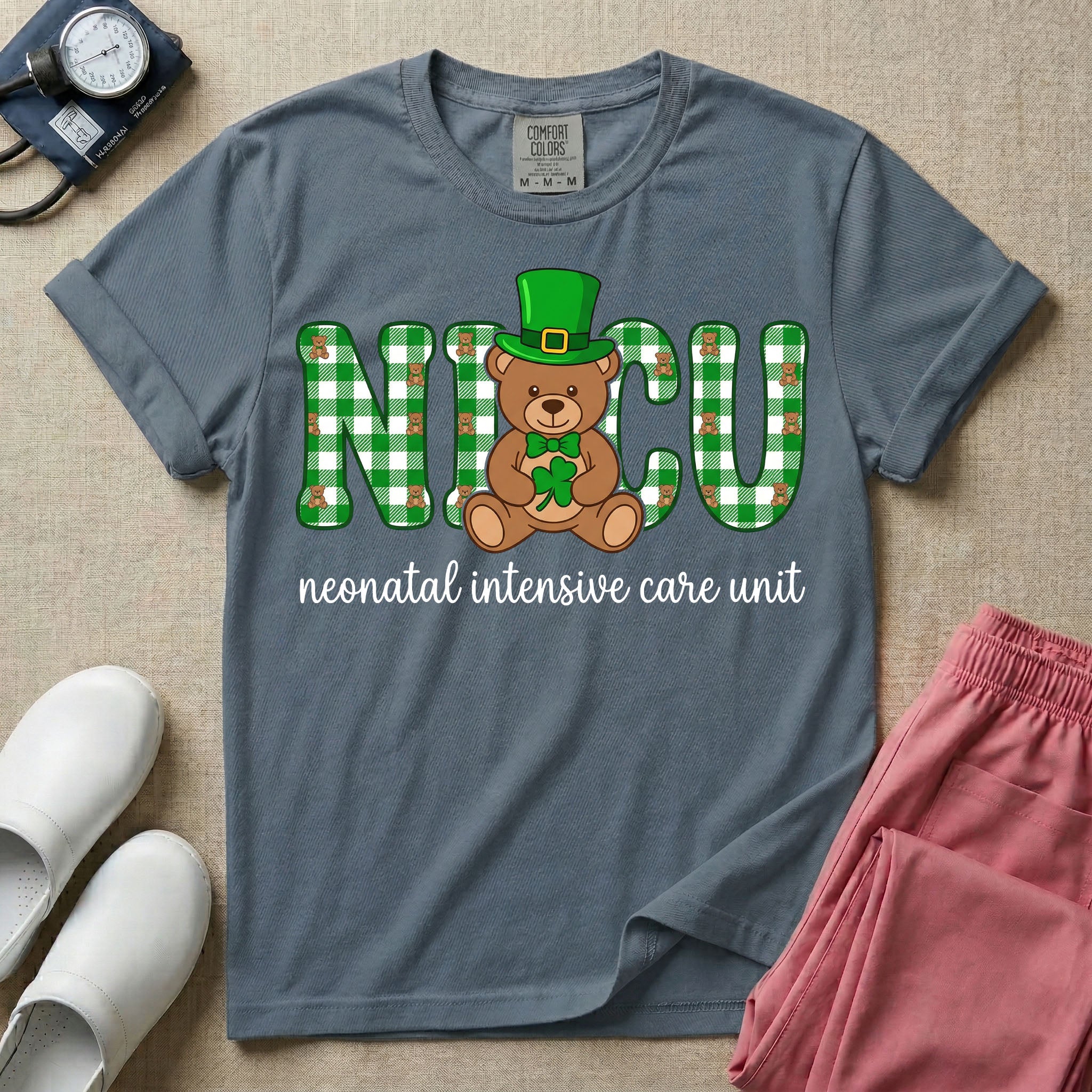 A graphic for a Neonatal Intensive Care Unit featuring the word 'NICU' in green and white plaid patterned letters, with a cute brown teddy bear wearing a leprechaun hat and holding a shamrock sitting in the middle, and the cursive text 'neonatal intensive care unit' underneath.