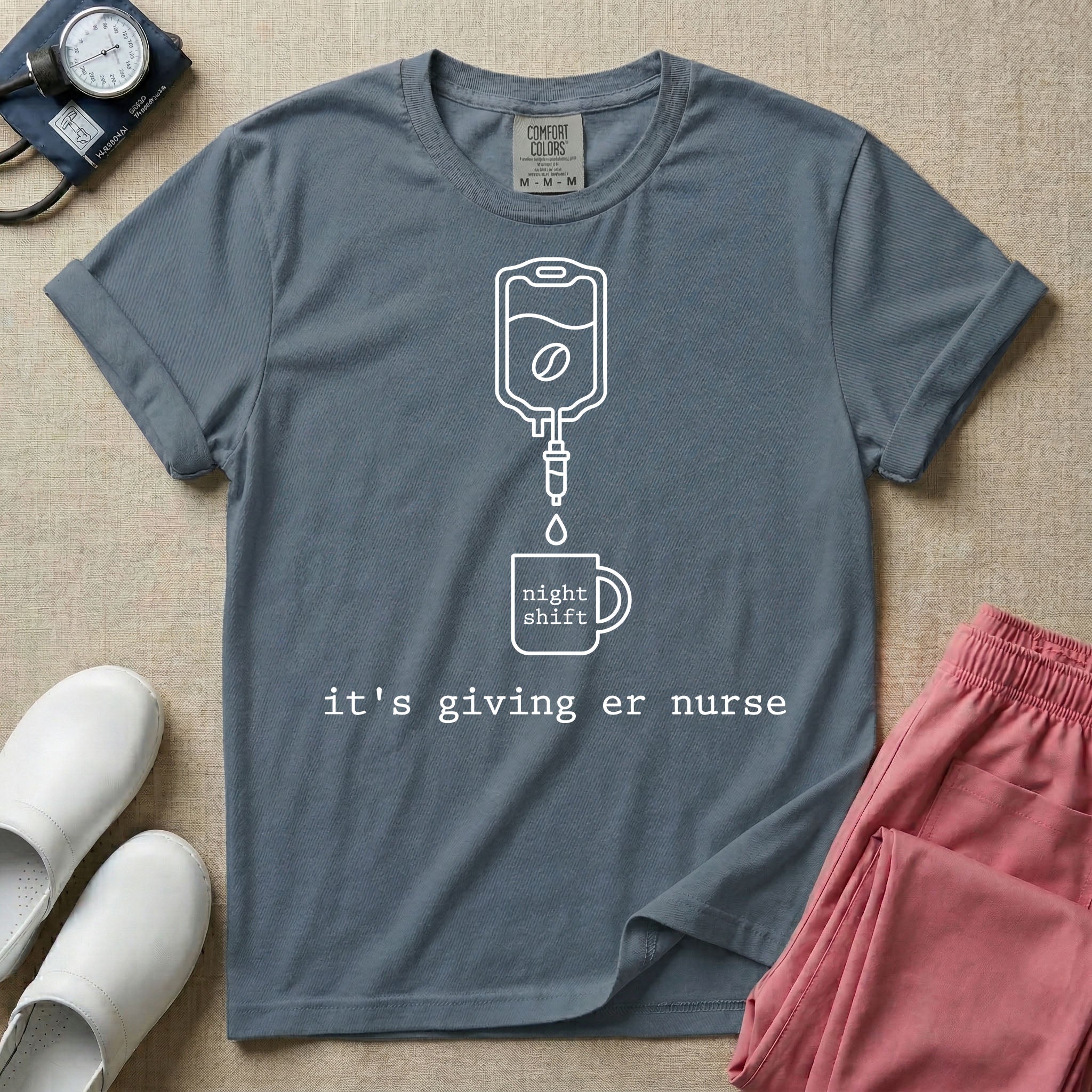 A funny minimalist ER nursing t-shirt featuring a white line drawing of an IV bag containing a coffee bean dripping into a mug labeled "night shift", sitting above the lower-case typewriter text "it's giving er nurse".