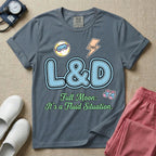 A humorous Labor and Delivery nurse graphic featuring large, light blue varsity-style letters spelling L&D with a pink dashed outline, surrounded by small patch-like icons of a baby and a lightning bolt, sitting above cursive text that reads Full Moon: It's a Fluid Situation.