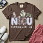 A funny t-shirt for NICU nurses featuring the large text "NICU" patterned with purple stripes and pink leopard print containing grumpy cat faces, accompanied by graphics of an IV bag with a pink bow, a steaming coffee cup reading "NICU FUEL", a green flag saying "Code Grumpy", and the bottom text "Small Babies. Shorter Fuses."