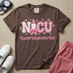 Retro coquette style t-shirt graphic featuring decorative pink 'NICU' text with checkerboard and heart patterns, incorporating a baby bottle with a bow and hearts, and the cursive text 'Neonatal Intensive Care Unit' below.