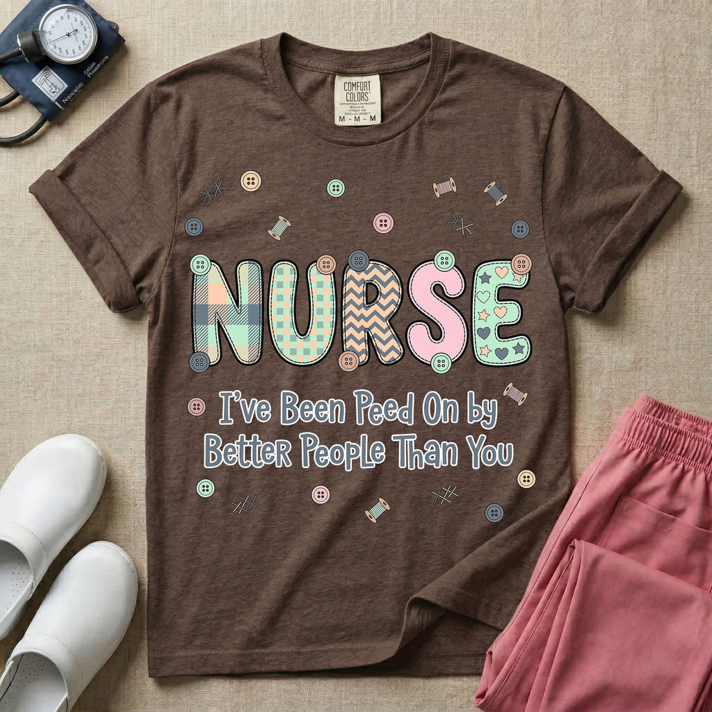 A humorous t-shirt for nurses featuring the word "NURSE" in colorful boho patterned letters above the funny phrase "I've Been Peed On by Better People Than You", surrounded by small abstract floral shapes.