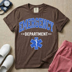 A classic varsity-style t-shirt for emergency room nurses featuring the word "EMERGENCY" in a large, arched blue collegiate font above the word "DEPARTMENT", centered over a blue Star of Life medical symbol.