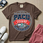 A t-shirt featuring a circular badge design with the text PACU SQUAD in block letters, medical icons like a heart monitor and stethoscope, and the phrase Waking You Up Is What We Do.