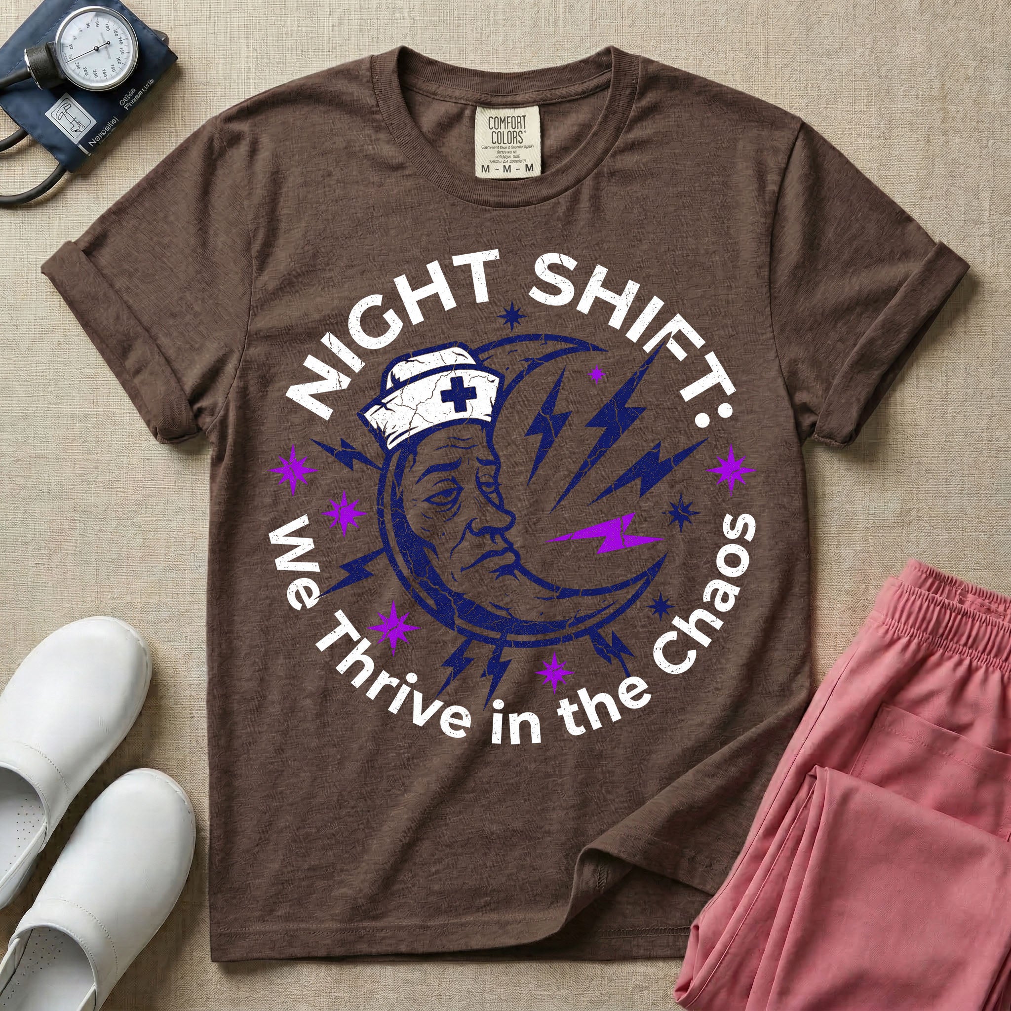General nursing night shift nurse t-shirt with a retro purple moon wearing a nurse cap and we thrive in the chaos graphic in espresso color.