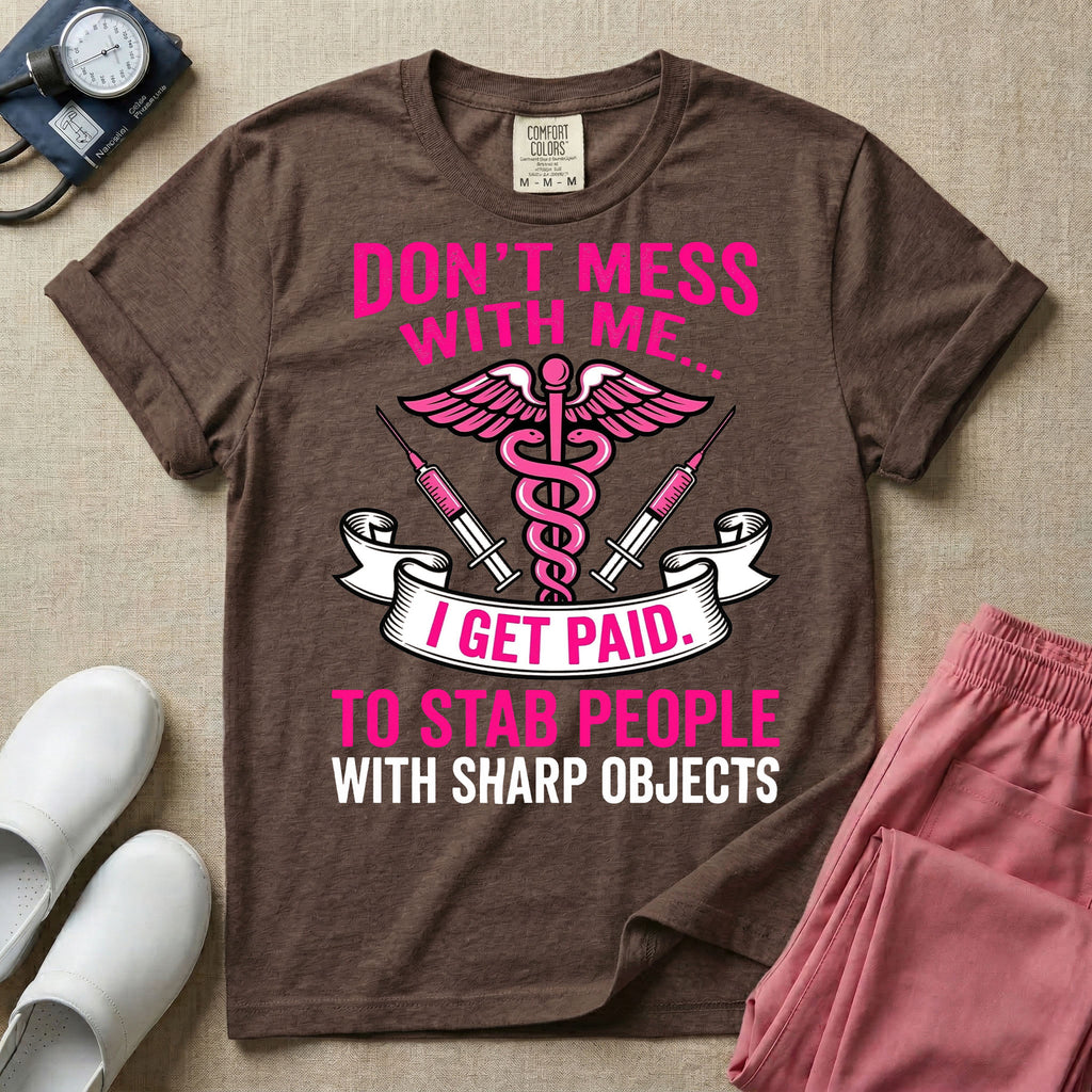 General nursing and ER t-shirt featuring a pink and black caduceus medical symbol flanked by two syringes alongside the humorous text "DON'T MESS WITH ME... I GET PAID TO STAB PEOPLE WITH SHARP OBJECTS".