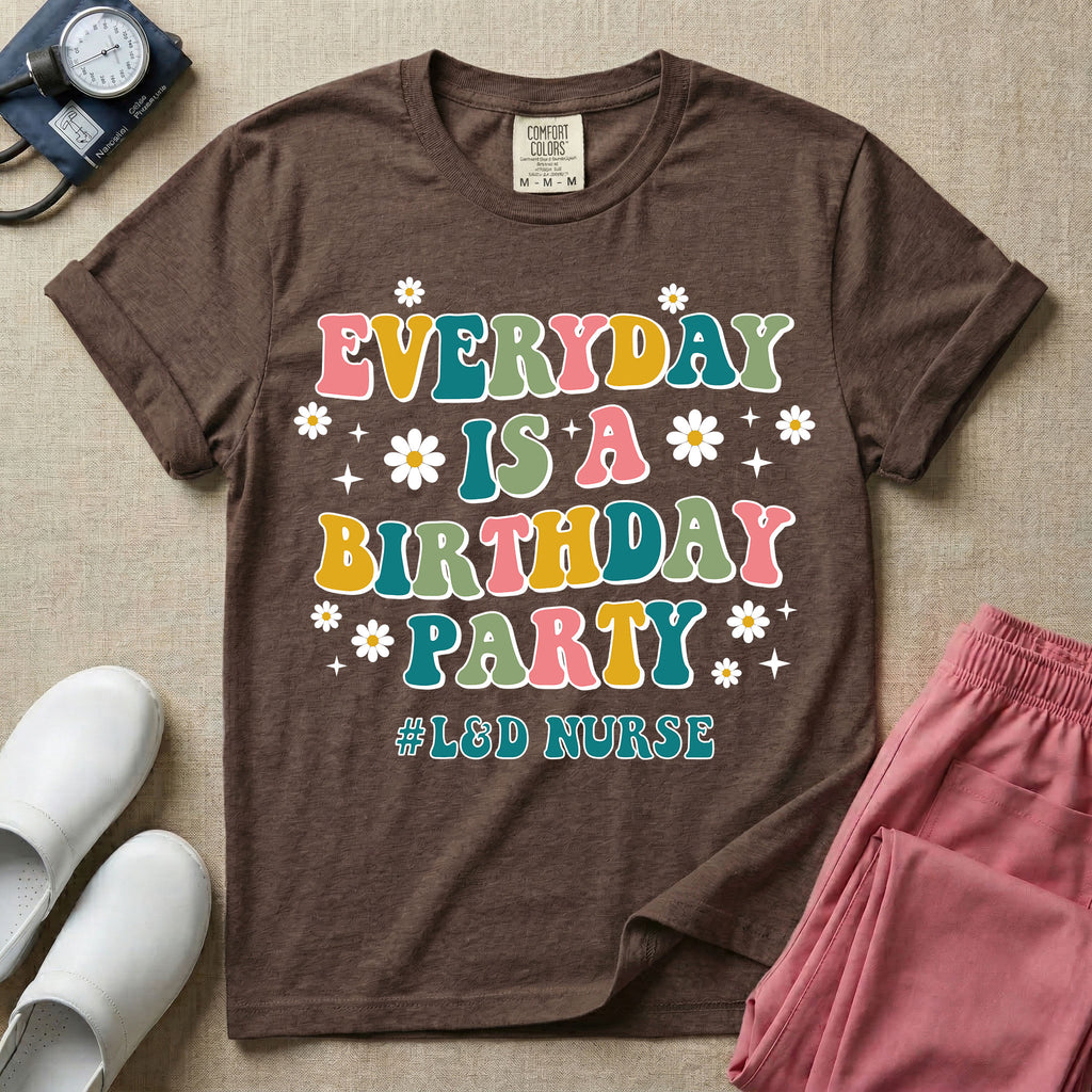 A retro graphic tee for labor and delivery nurses featuring bubble lettering that reads "EVERYDAY IS A BIRTHDAY PARTY #L&D NURSE" surrounded by small daisies and stars.