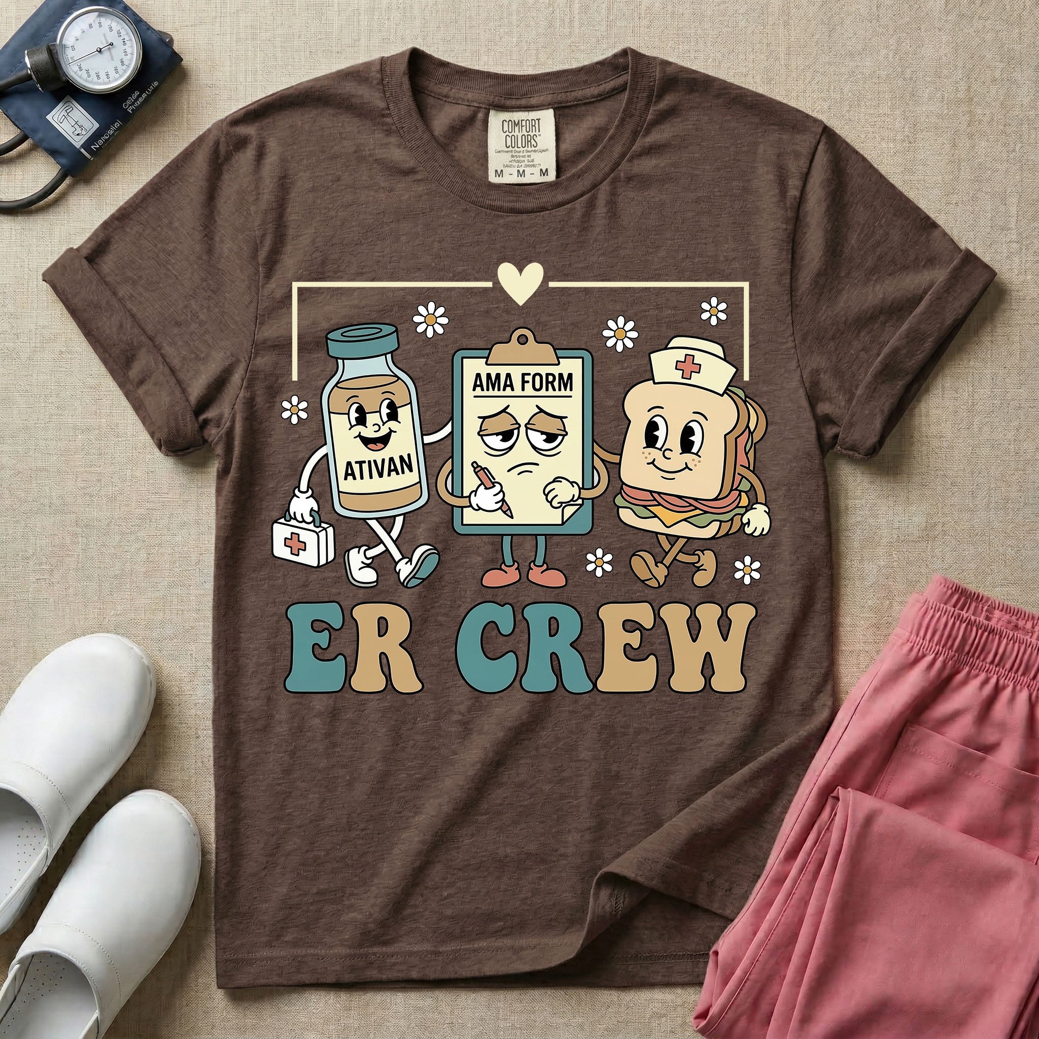A retro-style t-shirt for emergency room nurses featuring the text "ER CREW" below a vintage cartoon illustration of a medicine bottle, a grumpy clipboard holding an AMA form, and a sandwich wearing a nurse cap walking together.