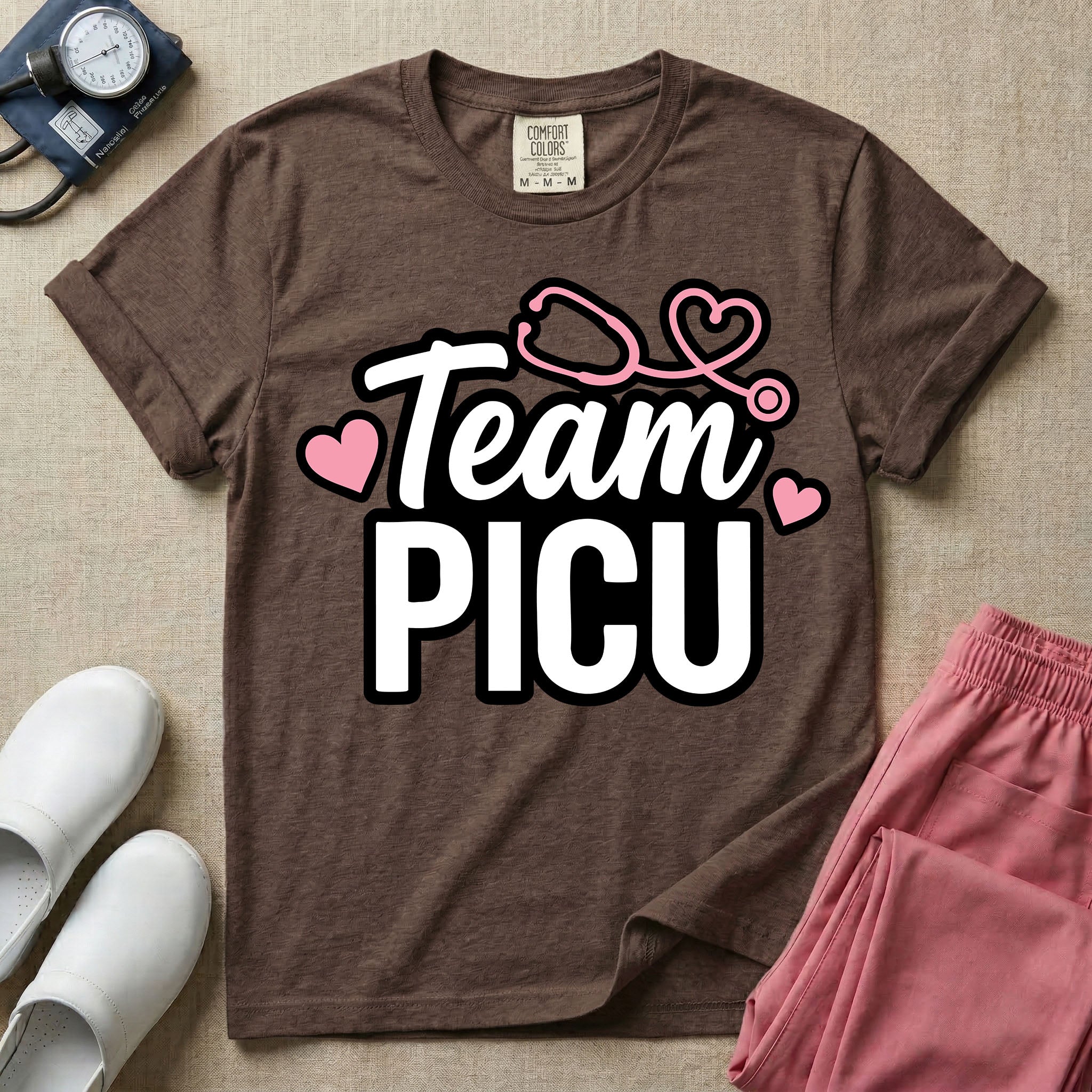 A descriptive graphic tee for pediatric intensive care nurses featuring the text "Team PICU" in bold white lettering, accented with pink hearts and a pink stethoscope design.
