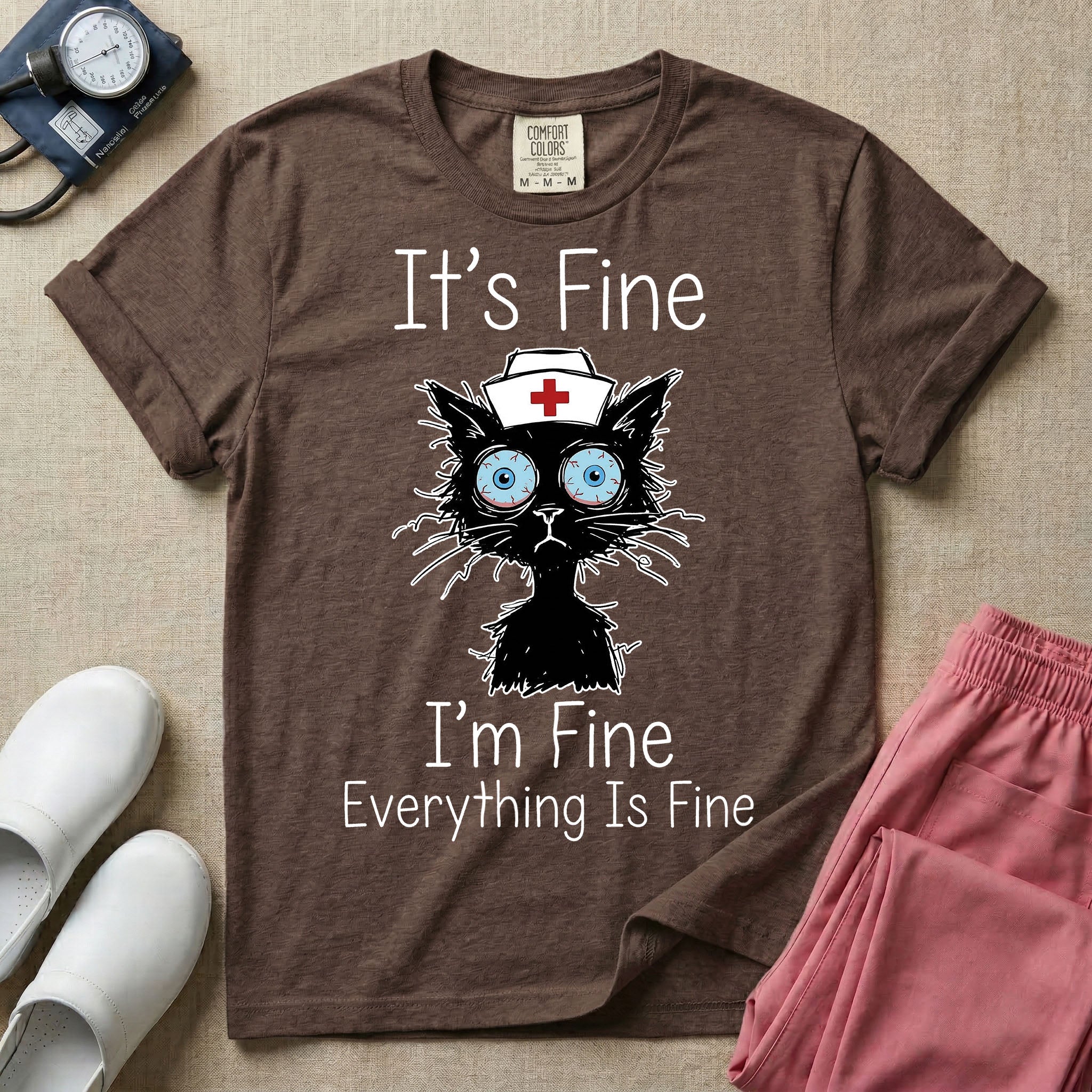 General nursing t-shirt featuring a humorous graphic of a frazzled black cat wearing a medical cross nurse cap alongside the text "It's Fine I'm Fine Everything Is Fine".