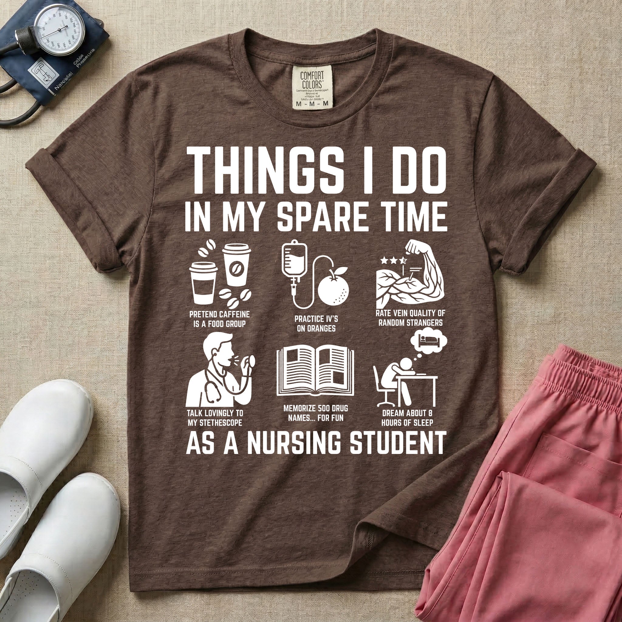 A t-shirt featuring the text THINGS I DO IN MY SPARE TIME AS A NURSING STUDENT surrounded by humorous line-art icons depicting studying, drinking coffee, and lacking sleep.