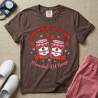 A t-shirt featuring two jars of strawberry jam surrounded by small hearts and strawberries with the text THE NICU IS MY JAM arched above and Neonatal ICU Nurse written in a retro script below.