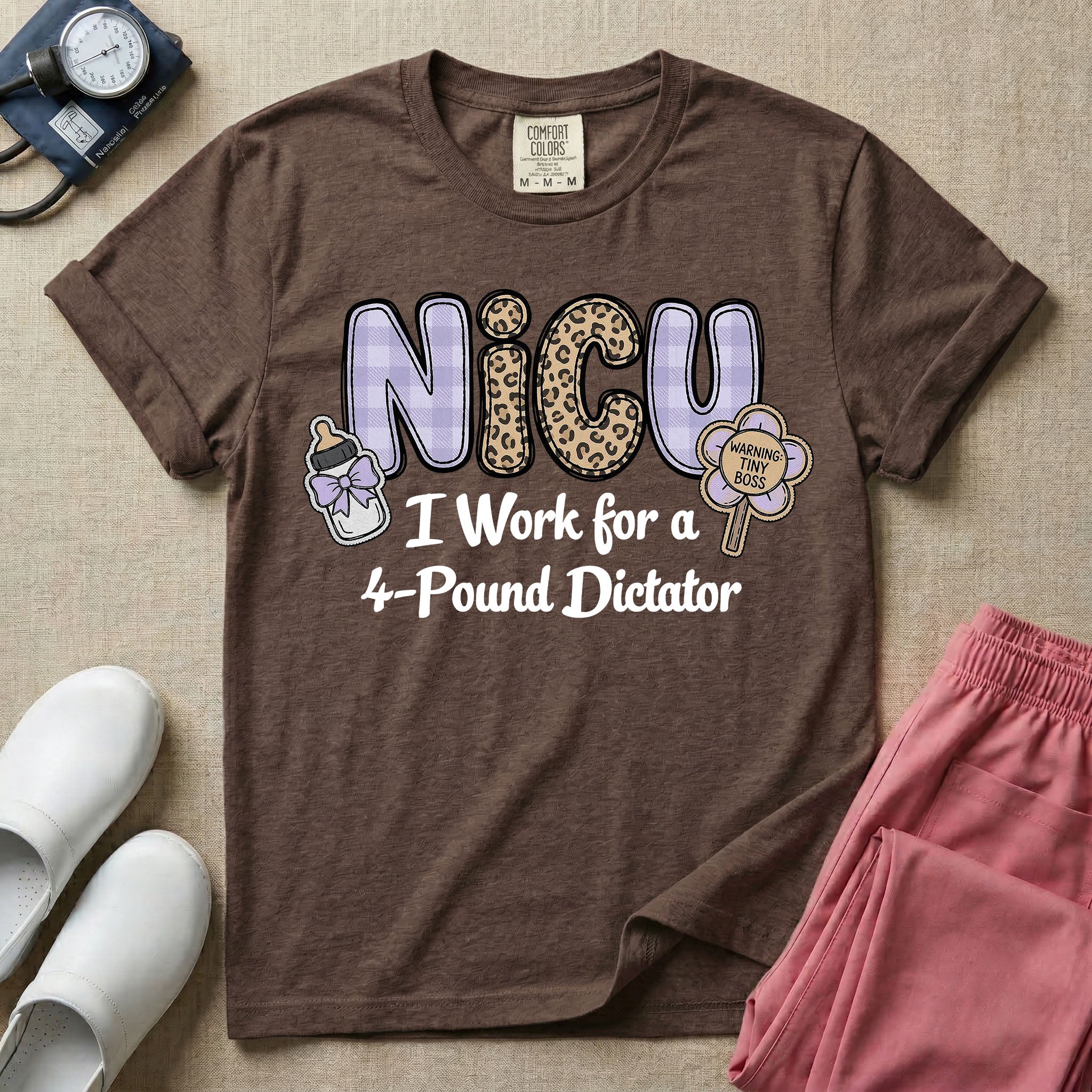 A funny t-shirt for NICU nurses featuring the text "NICU I Work for a 4-Pound Dictator" designed with purple plaid and leopard print letters, accompanied by graphics of a baby bottle with a bow and a rattle that says "WARNING: TINY BOSS".