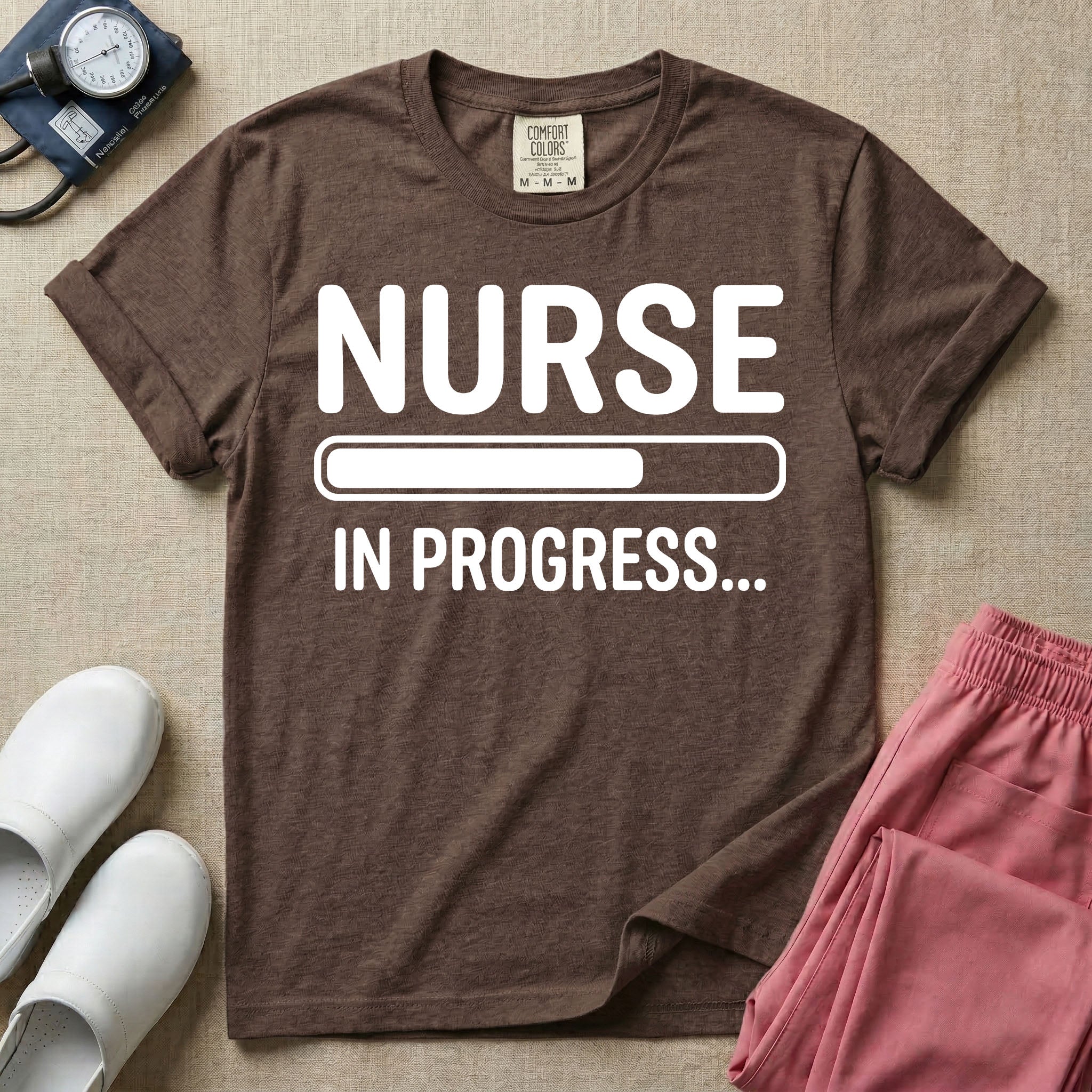 General nursing student t-shirt featuring a white loading bar graphic and the text "NURSE IN PROGRESS..." on a dark gray garment, in espresso color.