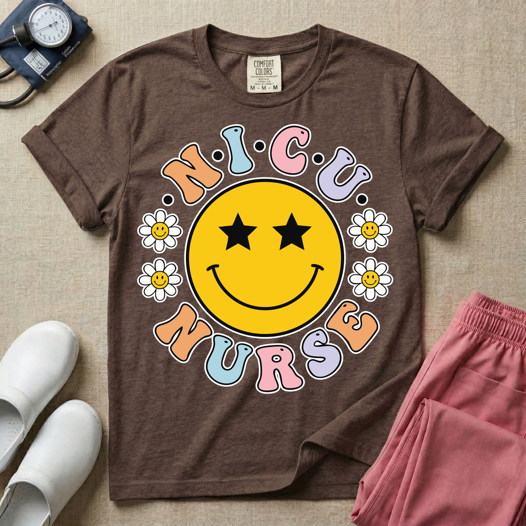 A t-shirt featuring a large yellow smiley face with star eyes surrounded by smiley face daisies and the text N.I.C.U. NURSE in pastel retro bubble lettering.