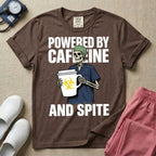 A humorous graphic for general nursing featuring an illustration of a skeleton wearing a green scrub cap and dark blue scrubs, holding a large white coffee cup with a yellow biohazard symbol, with the stacked text 'POWERED BY CAFFEINE' above it and 'AND SPITE' below it.