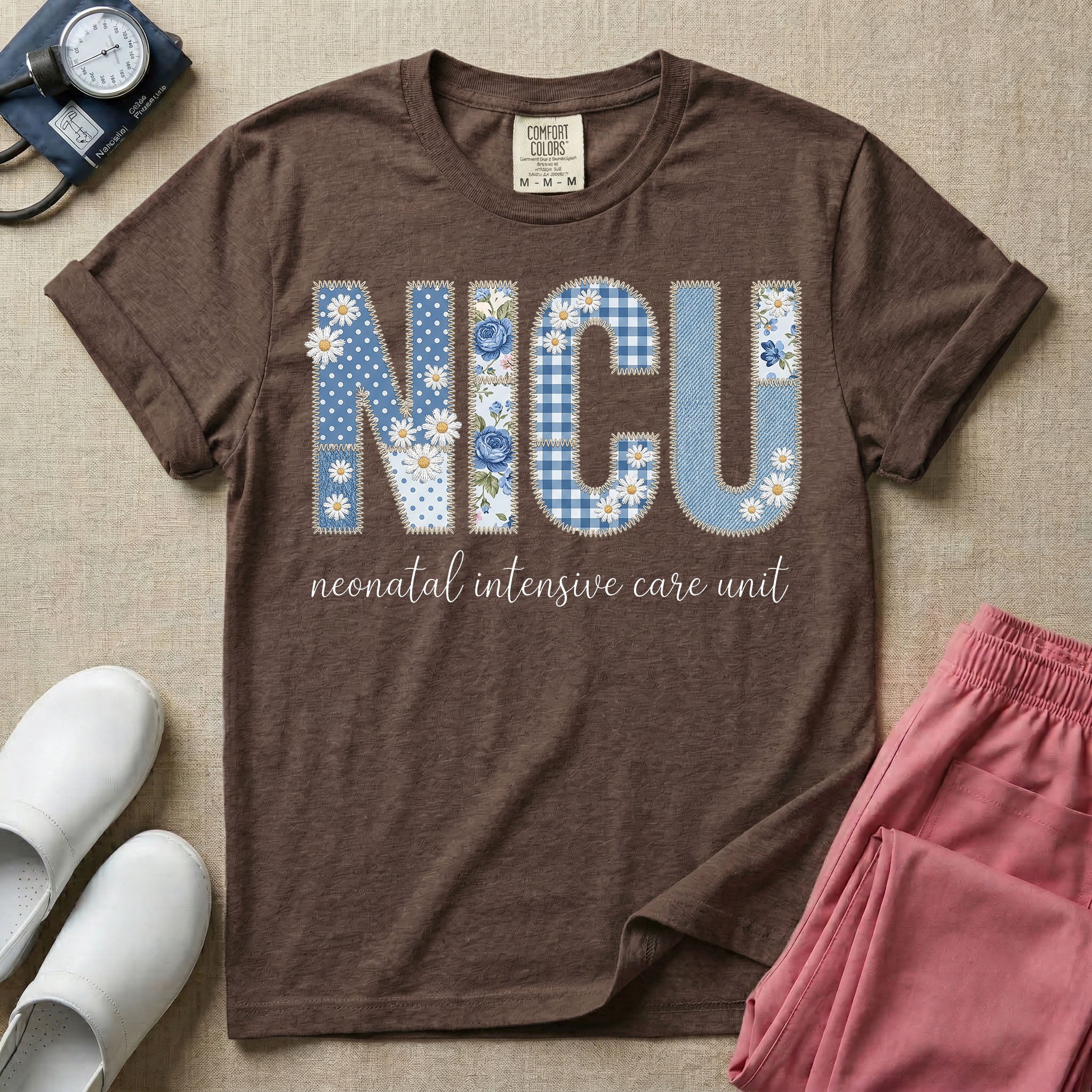 Neonatal Intensive Care Unit NICU nursing t-shirt featuring a faux-embroidery graphic of the letters NICU filled with blue floral and checkered patterns, positioned above the cursive text "neonatal intensive care unit".