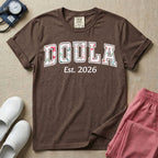 A personalized Doula graphic featuring the word DOULA in large, arched varsity-style letters filled with a delicate pink and green floral pattern, positioned above customizable text that reads Est. 2026.