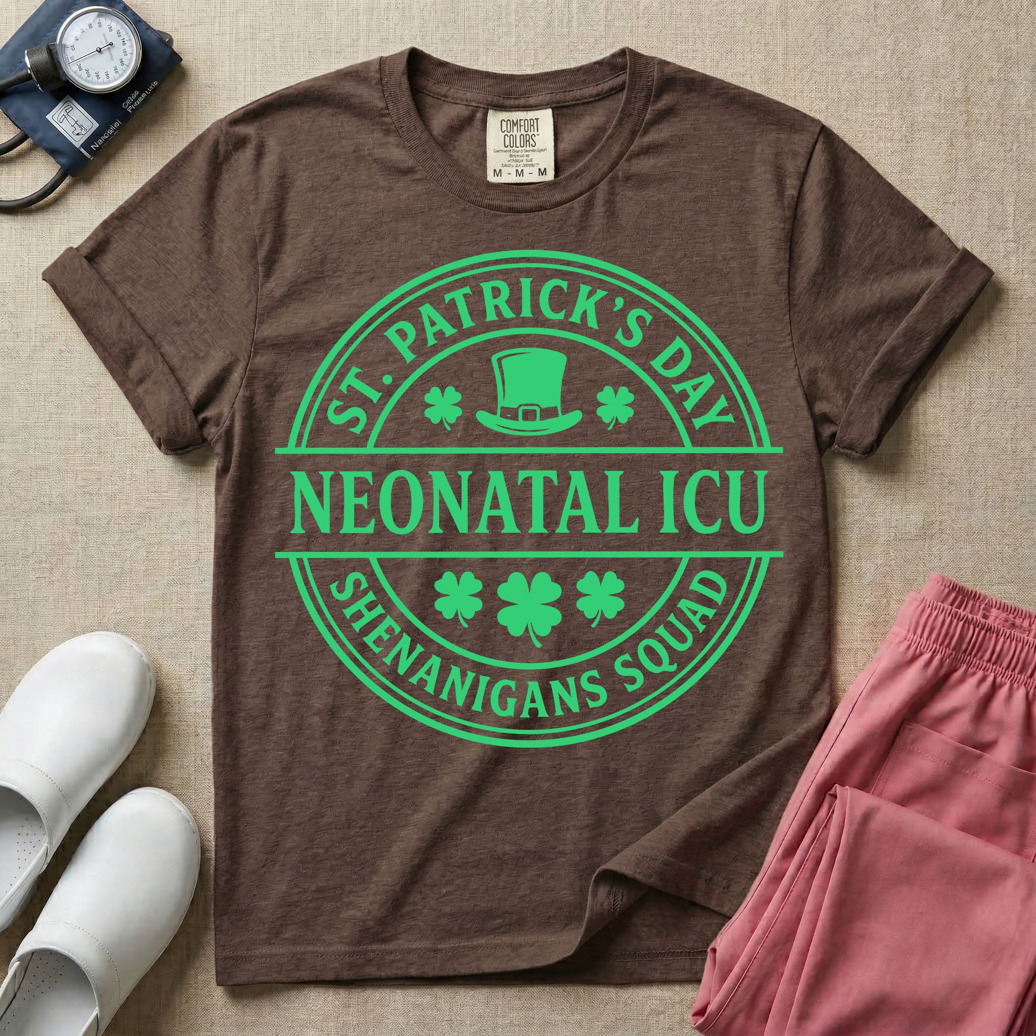 A circular green graphic featuring a leprechaun hat, shamrocks, and the text ST. PATRICK'S DAY SHENANIGANS SQUAD surrounding a center banner that reads NEONATAL ICU.