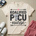 A funny pediatric intensive care nursing t-shirt featuring the pun text "KOALIFIED PICU nurse" with a cute koala graphic replacing the letter I in PICU, framed by decorative arrows and a pink medical cross.