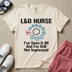 A humorous Labor and Delivery nurse t-shirt featuring a cervical dilation chart graphic highlighting 10cm, with the text "L&D NURSE" at the top and "I've Seen It All And I'm Still Not Impressed" at the bottom.