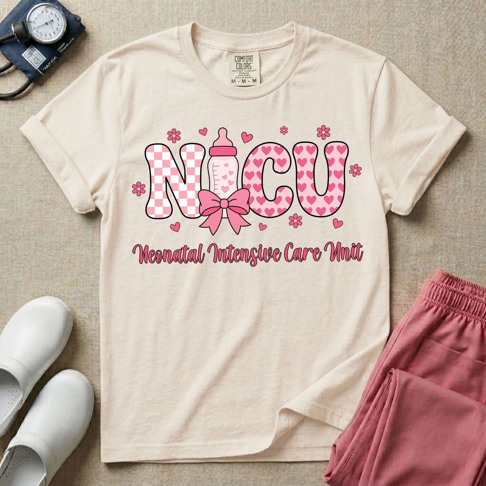 Retro coquette style t-shirt graphic featuring decorative pink 'NICU' text with checkerboard and heart patterns, incorporating a baby bottle with a bow and hearts, and the cursive text 'Neonatal Intensive Care Unit' below.