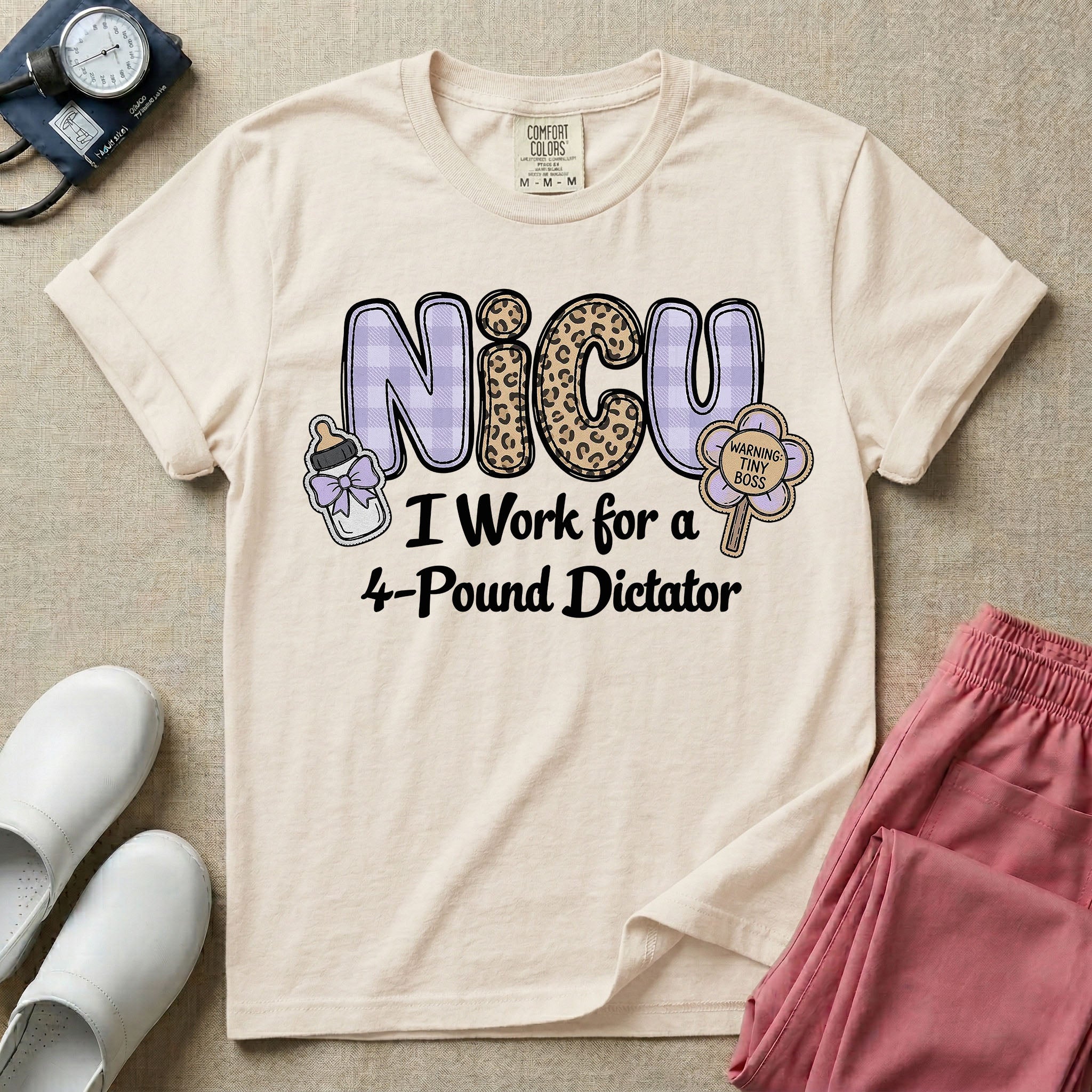 A funny t-shirt for NICU nurses featuring the text "NICU I Work for a 4-Pound Dictator" designed with purple plaid and leopard print letters, accompanied by graphics of a baby bottle with a bow and a rattle that says "WARNING: TINY BOSS".