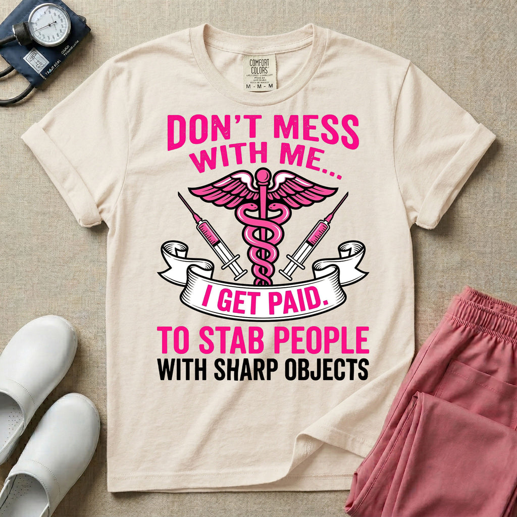 General nursing and ER t-shirt featuring a pink and black caduceus medical symbol flanked by two syringes alongside the humorous text "DON'T MESS WITH ME... I GET PAID TO STAB PEOPLE WITH SHARP OBJECTS".