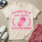 A humorous graphic tee for labor and delivery nurses featuring an illustration of a peanut ball wearing a cowboy hat, framed by laurel branches, along with the text "IN A WORLD FULL OF semi-fowlers BE A FLYING COWGIRL".