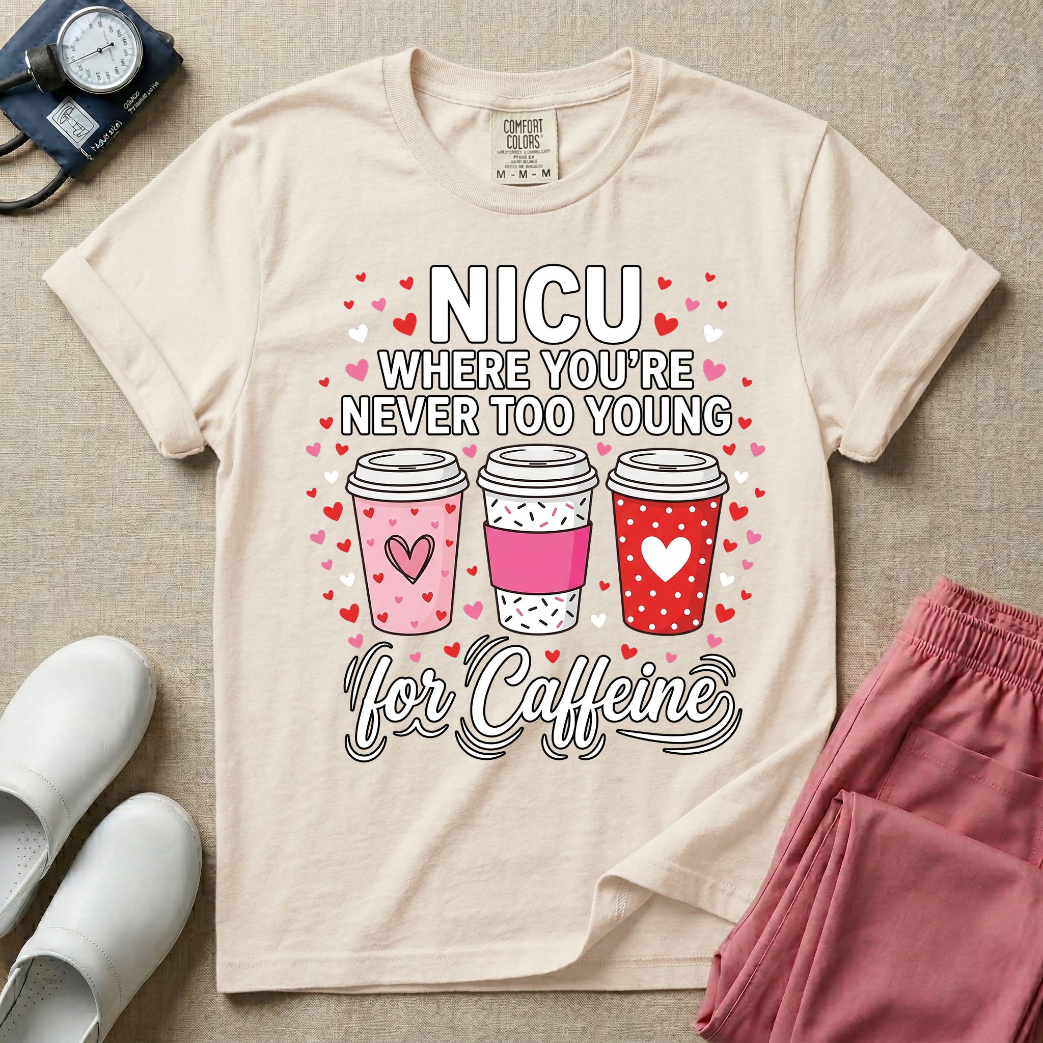 A Valentine's Day themed graphic for a Neonatal Intensive Care Unit featuring the text 'NICU WHERE YOU'RE NEVER TOO YOUNG' stacked above three to-go coffee cups decorated with heart patterns, with 'for Caffeine' written in script at the bottom, all surrounded by small red and pink hearts.