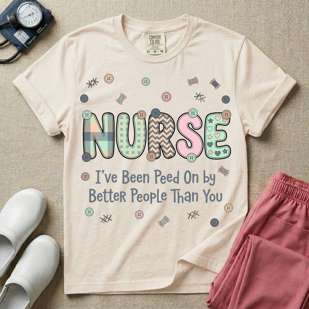 A humorous t-shirt for nurses featuring the word "NURSE" in colorful boho patterned letters above the funny phrase "I've Been Peed On by Better People Than You", surrounded by small abstract floral shapes.